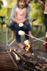 Familie röstet Marshmallows beim Zelten im Wald - CAVF48441