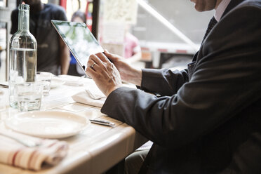 Seitenansicht eines Geschäftsmannes, der einen Tablet-Computer benutzt, während er am Tisch im Restaurant sitzt - CAVF48482