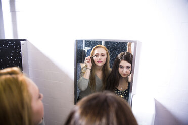 Friends doing make-up in restroom at high school seen through mirror - CAVF48529