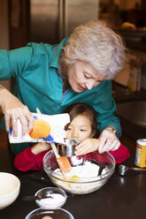 Ältere Frau mit Enkelin bei der Essenszubereitung zu Hause - CAVF48600