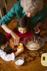 Hochformatige Ansicht einer Großmutter mit Kindern, die zu Hause Kekse zubereiten - CAVF48602