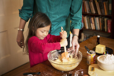 Midsection of grandmother with girl preparing cookies at home during Christmas - CAVF48603
