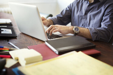Mittelteil eines Mannes, der einen Laptop benutzt, während er im Büro sitzt - CAVF48639