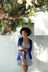 Woman looking away while standing against retaining wall - CAVF48686