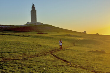 Mann joggt bei Sonnenaufgang auf einem Feld - CAVF48701