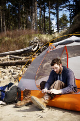 Man wearing shoes while sitting in tent - CAVF48736