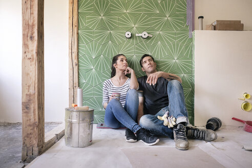 Ehepaar renoviert neues Haus, sitzt auf dem Boden und plant das Badezimmer - PESF01046