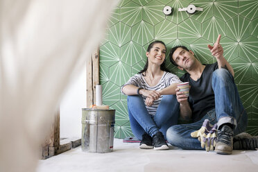 Ehepaar renoviert neues Haus, sitzt auf dem Boden und plant das Badezimmer - PESF01047