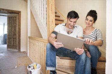 Junges Paar bei der Renovierung eines neuen Hauses, auf der Treppe sitzend, mit digitalem Tablet - PESF01061