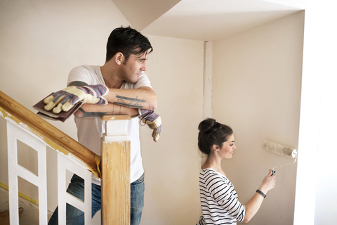 Junges Paar renoviert neues Haus, streicht Treppenhaus, lizenzfreies Stockfoto