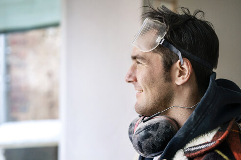 Porträt eines Handwerkers, der eine Wohnung renoviert, Blick durch ein Fenster - PESF01067