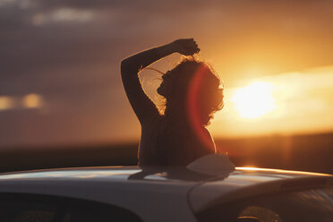 Woman outside the car at sunset, raised arm - JPF00304
