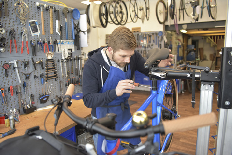 Fahrradmechaniker bei der Arbeit in seiner Reparaturwerkstatt, lizenzfreies Stockfoto