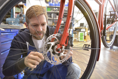 Fahrradmechaniker bei der Arbeit in seiner Reparaturwerkstatt - LYF00816