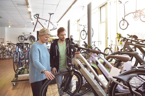 Verkäufer hilft Kunde mit E-Bike, lizenzfreies Stockfoto
