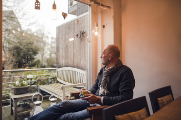 Senior man sitting at home, drinking coffee - GUSF00671