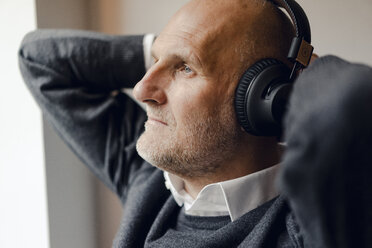 Senior man wearing headphones, listening music, portrait - GUSF00698