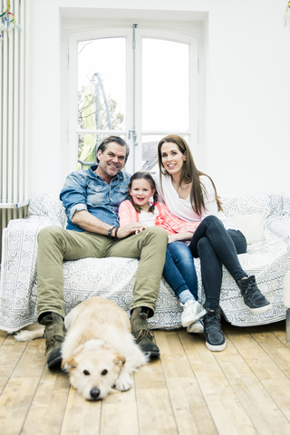 Porträt einer glücklichen Familie mit Hund im Wohnzimmer, lizenzfreies Stockfoto