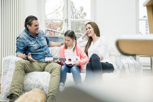 Glückliche Familie sitzt auf der Couch und macht Musik - MOEF01080