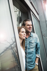 Smiling couple looking out of window - MOEF01087