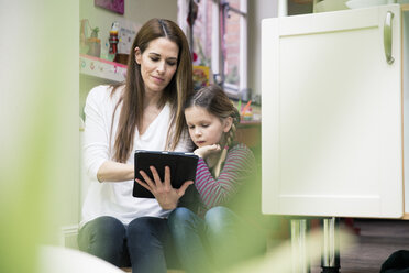 Mutter und Tochter nutzen gemeinsam ein Tablet zu Hause - MOEF01094