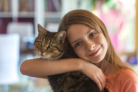 Porträt eines lächelnden Mädchens mit ihrer getigerten Katze, lizenzfreies Stockfoto