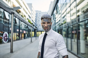 Young businessman with tattooed face walking in the city, portrait - ZEDF01329