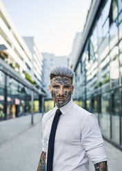 Junger Geschäftsmann mit tätowiertem Gesicht beim Spaziergang in der Stadt, Porträt - ZEDF01330