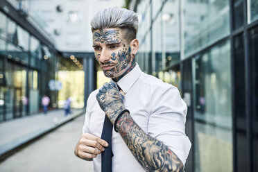 Young businessman with tattooed face, fastening tie - ZEDF01347