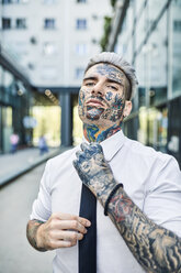 Young businessman with tattooed face, fastening tie - ZEDF01348