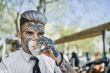 Young businessman with tattooed face, drinking coffee - ZEDF01350