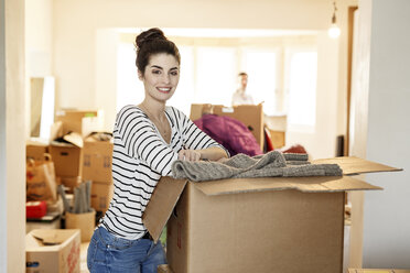 Young woman moving house, unpacking cardboard boxes - PESF01088
