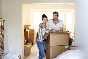 Young couple moving house, unpacking cardboard boxes - PESF01090