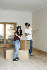 Couple moving into their new home, looking through VR glasses - PESF01093