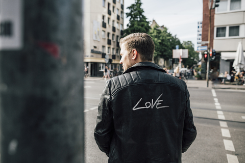 Back view of young man wearing black leather jacket with writing 'Love' stock photo