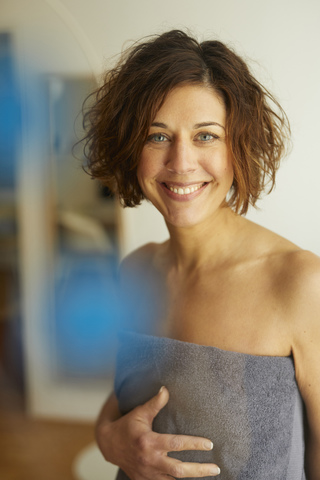 Portrait of smiling mature woman wrapped in a towel stock photo