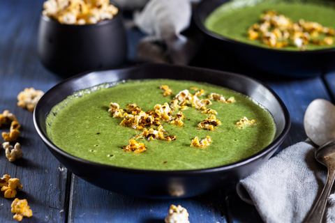 Vegane grüne Gemüsesuppe mit Spinat, Lauch und Erbsen, Chili-Popcorn, lizenzfreies Stockfoto