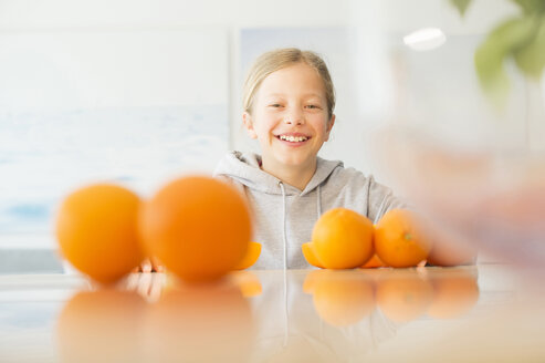 Porträt eines glücklichen Mädchens mit Orangen in der Küche - NEKF00030