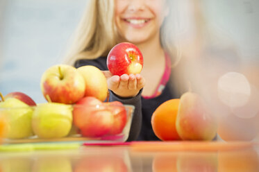 Smiling girl offering an apple - NEKF00035