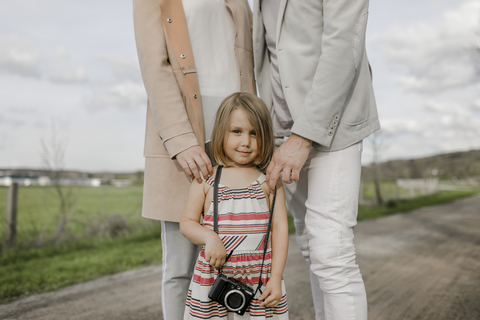 Porträt eines lächelnden kleinen Mädchens mit hinter ihr stehenden Eltern, lizenzfreies Stockfoto