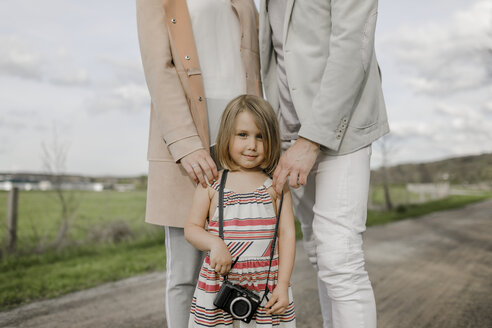Porträt eines lächelnden kleinen Mädchens mit hinter ihr stehenden Eltern - KMKF00236