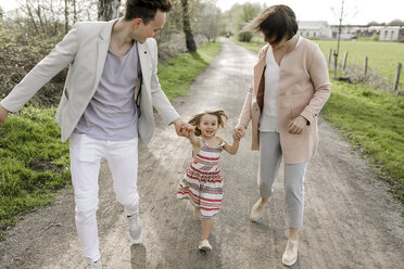 Little girl holding hands of parents while running - KMKF00237