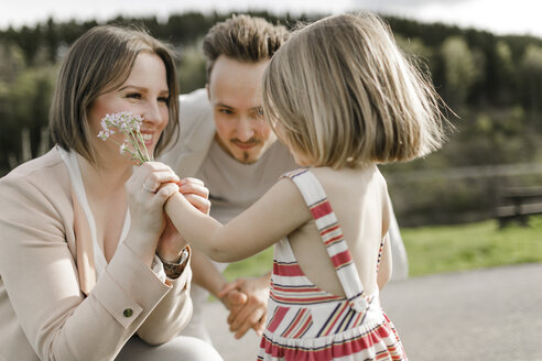 Kleines Mädchen schenkt Mutter Blumen, während ihr Vater zusieht - KMKF00240