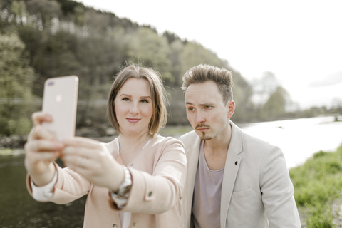 Portrait of young couple taking selfie with smartphone outdoors stock photo