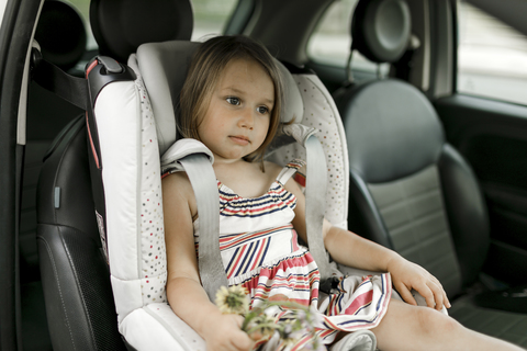 Porträt eines kleinen Mädchens, das im Kindersitz sitzt und wartet, lizenzfreies Stockfoto
