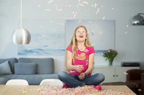 Mädchen sitzt auf Tisch, Bonbons fallen herunter - NEKF00039