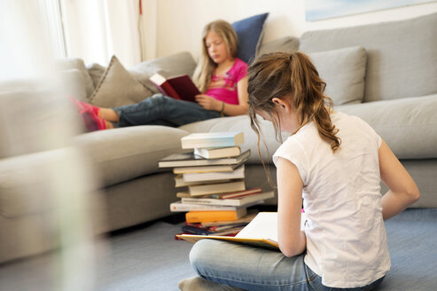 Zwei Mädchen sitzen im Wohnzimmer und lesen Bücher - NEKF00041