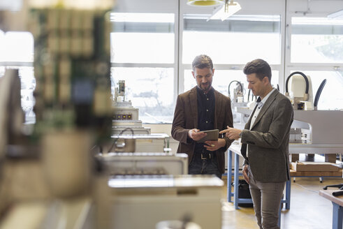Zwei Geschäftsleute mit Tablet im Gespräch in einer Fabrik - DIGF03967