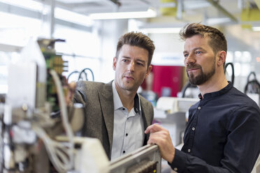 Two businessmen examining device in factory - DIGF03971