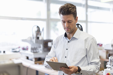 Mann benutzt Tablet in Fabrik - DIGF03973